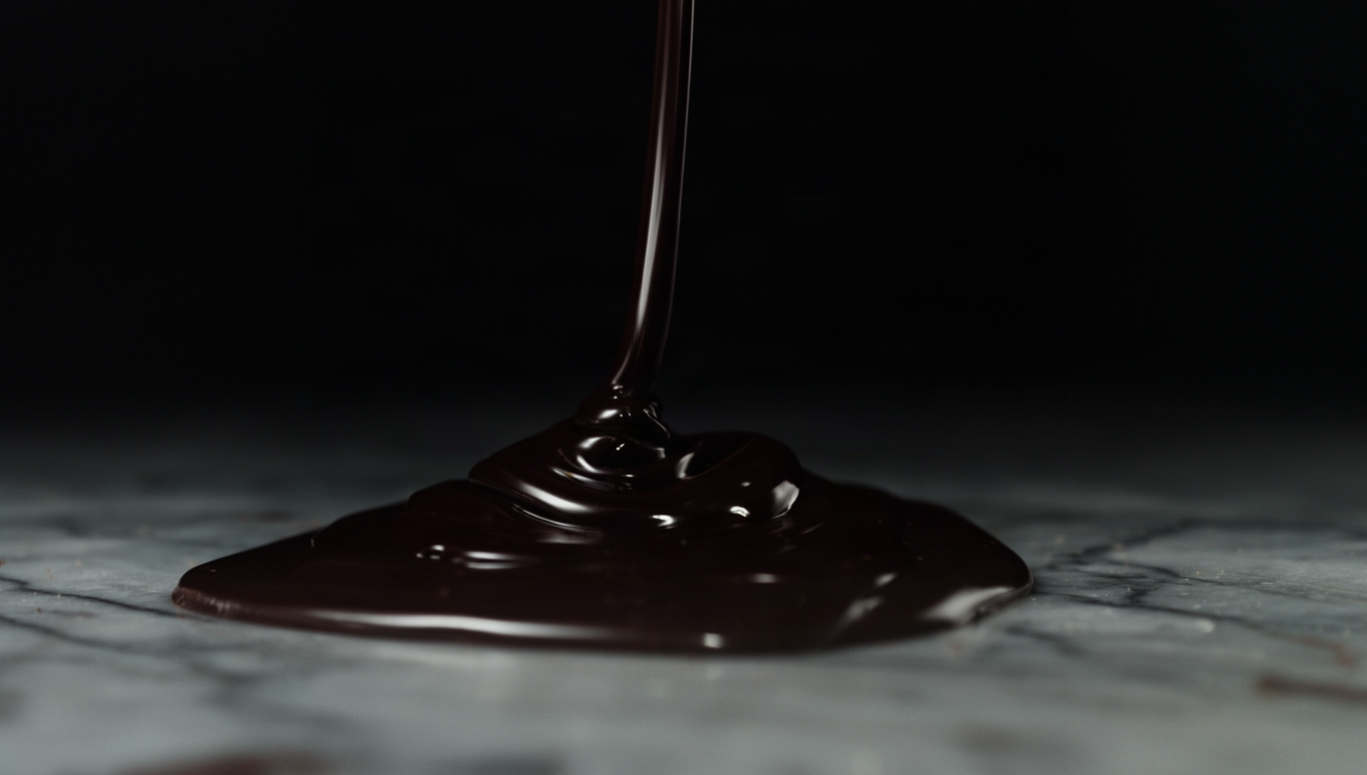 Chocolate negro de cobertura fundido vertido sobre mármol
